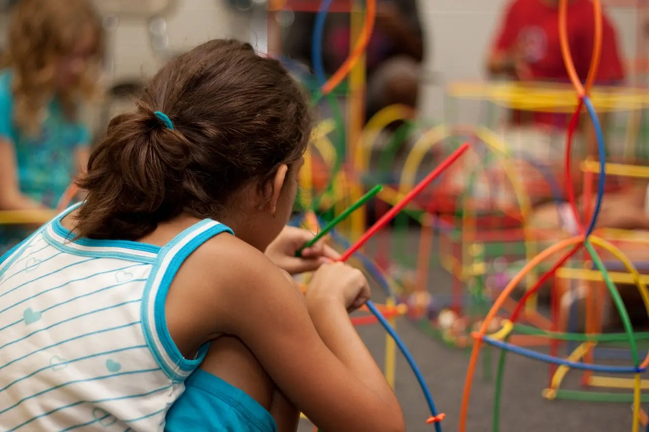 niña jugando con palitos de colores